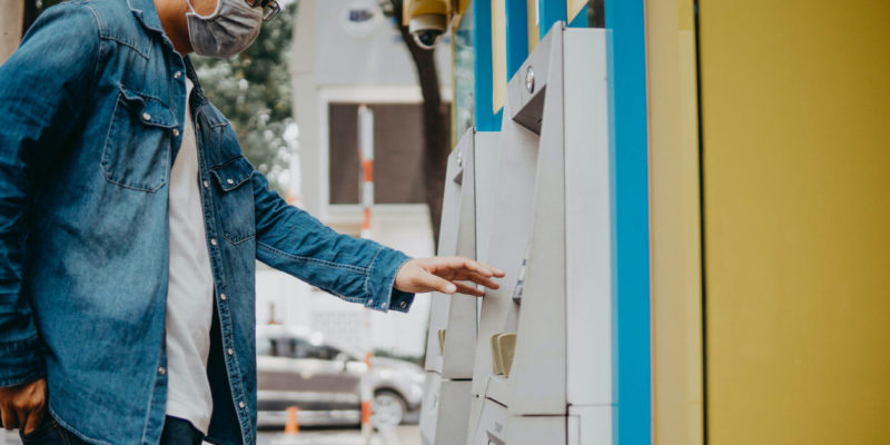 young asian man at ATM with mask on