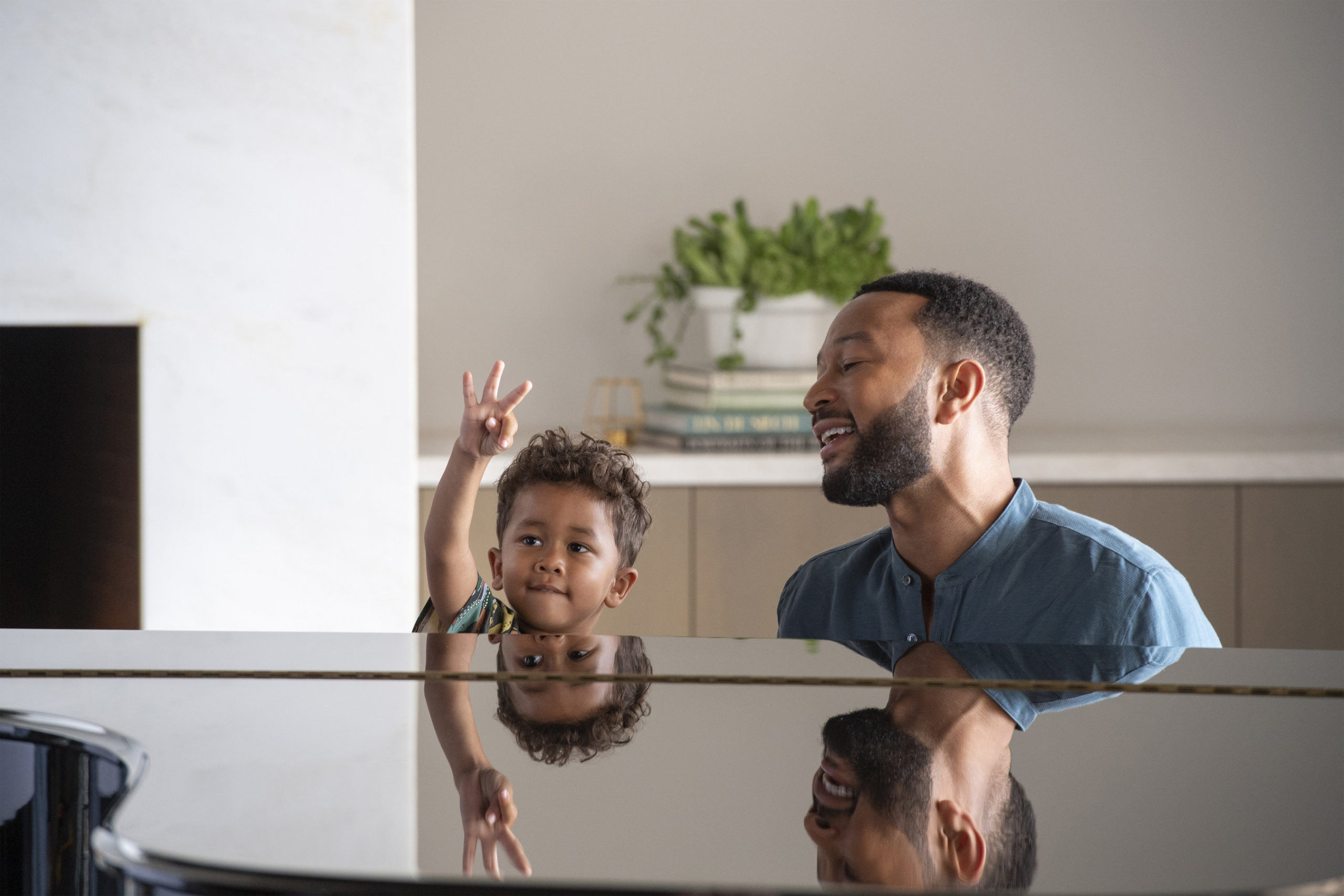 John Legend plays piano with his son sitting beside him in a new Vrbo commercial